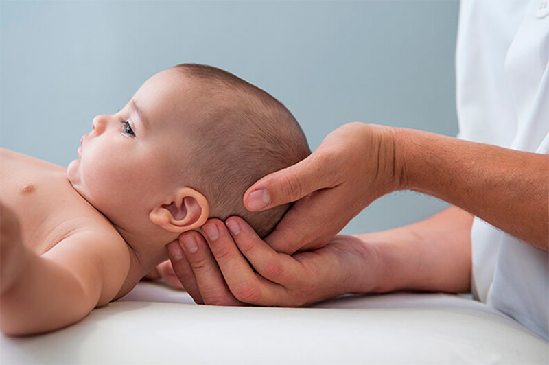 остеопат осматривает новорожденного