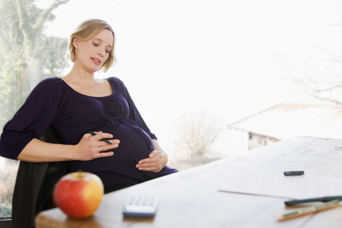 Беременная женщина сидит за столом