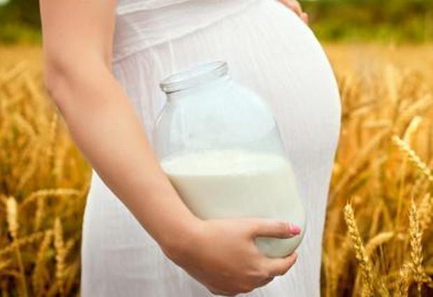 Беременная женщина держит банку с молоком