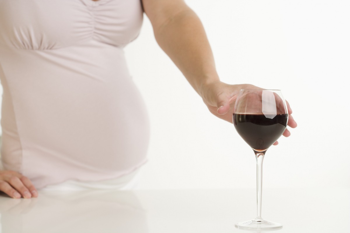 Беременная женщина берет бокал вина